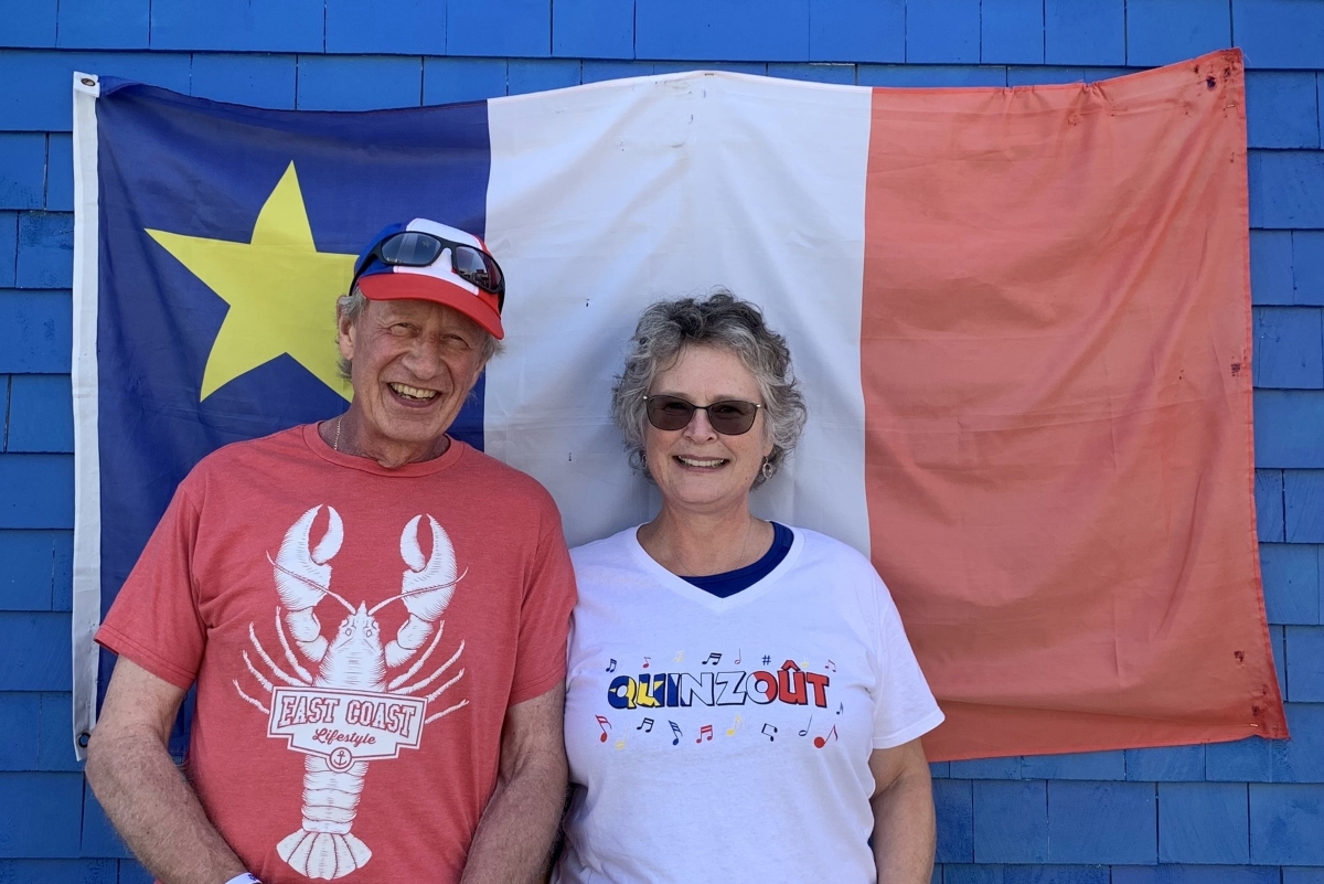 Cultural cross-currents: author and his wife dressed in Acadian garb and standing in front of an Acadian flag