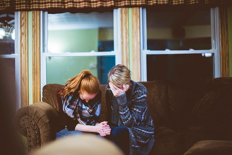 family conflict: two people sitting on a chesterfield with heads down, seemingly after a difficult conversation