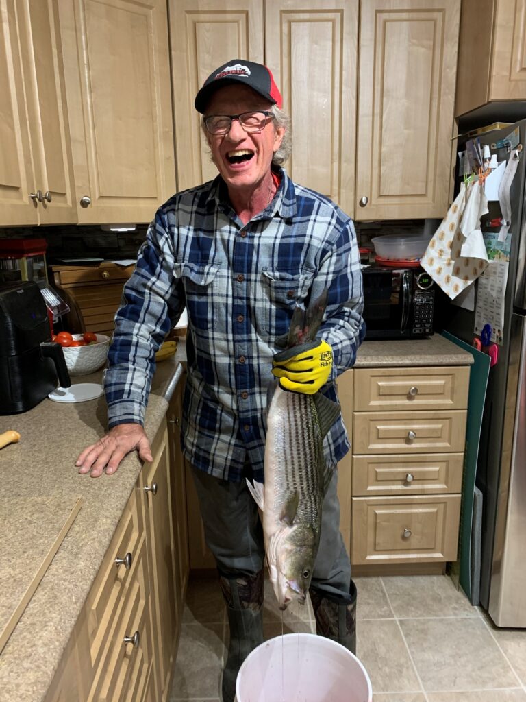 fishing: author in his kitchen holding a 60 cm striped bass by the tail