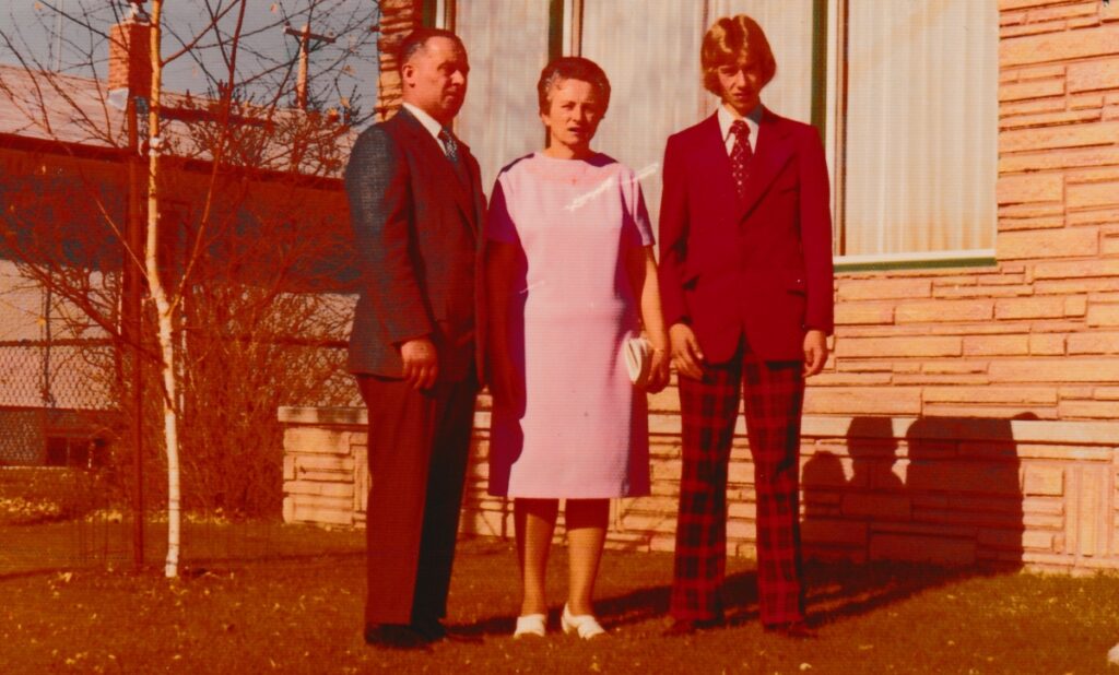 A man, a woman, and a teenager posing for a family picture in front of a house